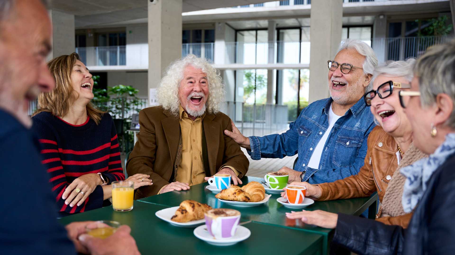 A senior couple sitting in a chair laughing with friends